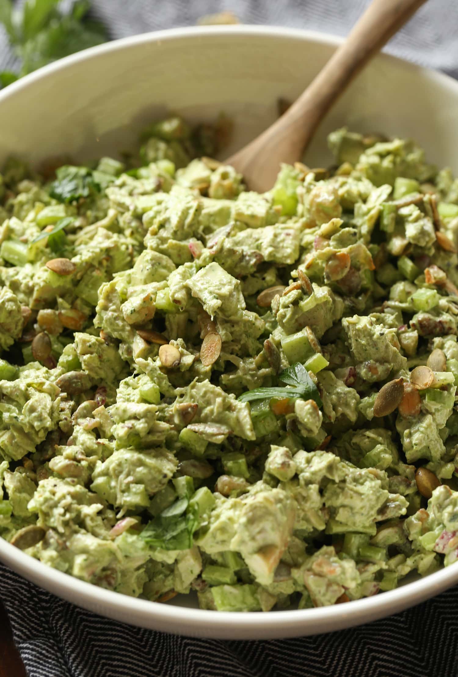 Ensalada de pollo diosa verde en un tazón grande con una cuchara de madera.