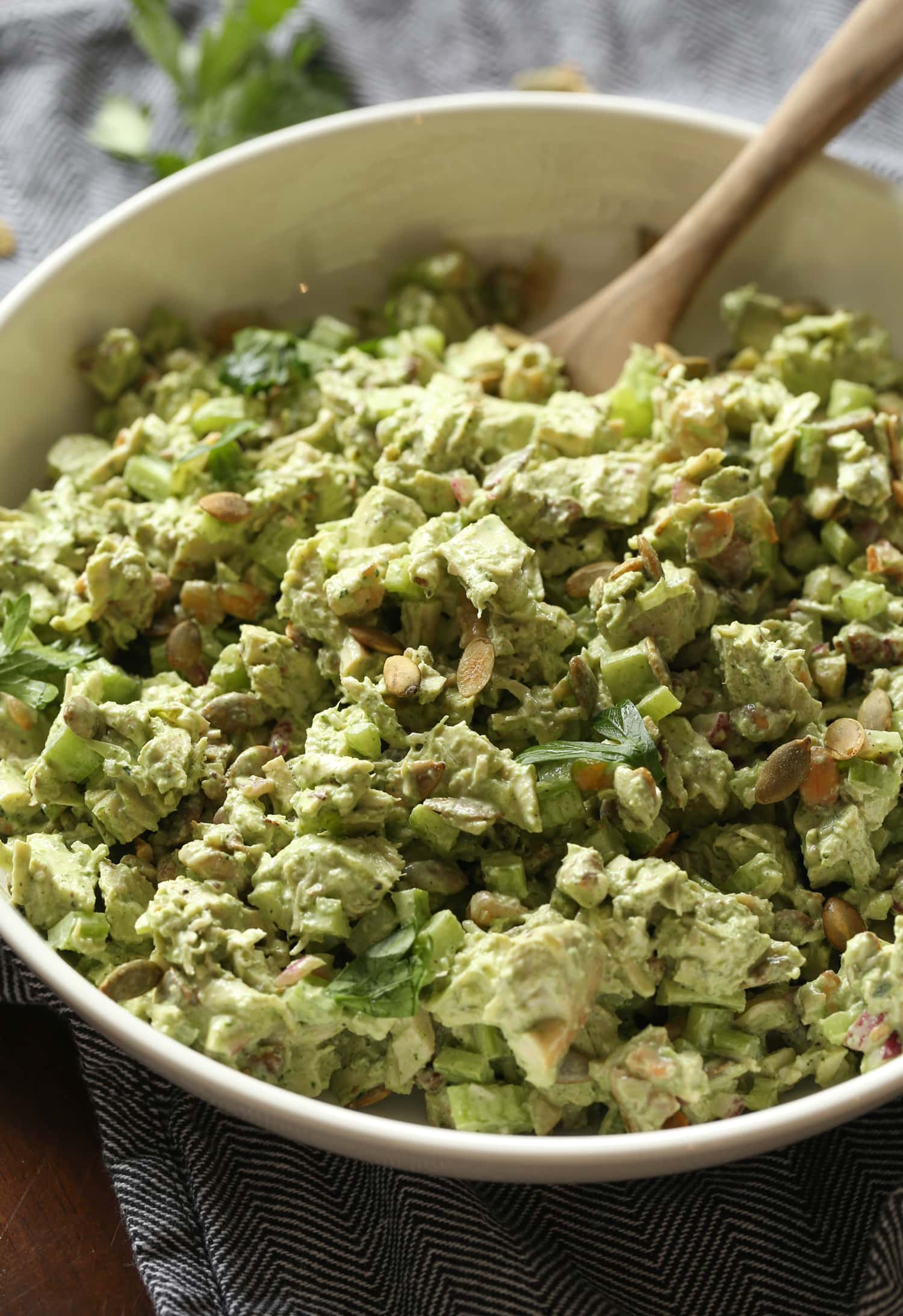 Ensalada de pollo diosa verde en un tazón grande con una cuchara de madera.