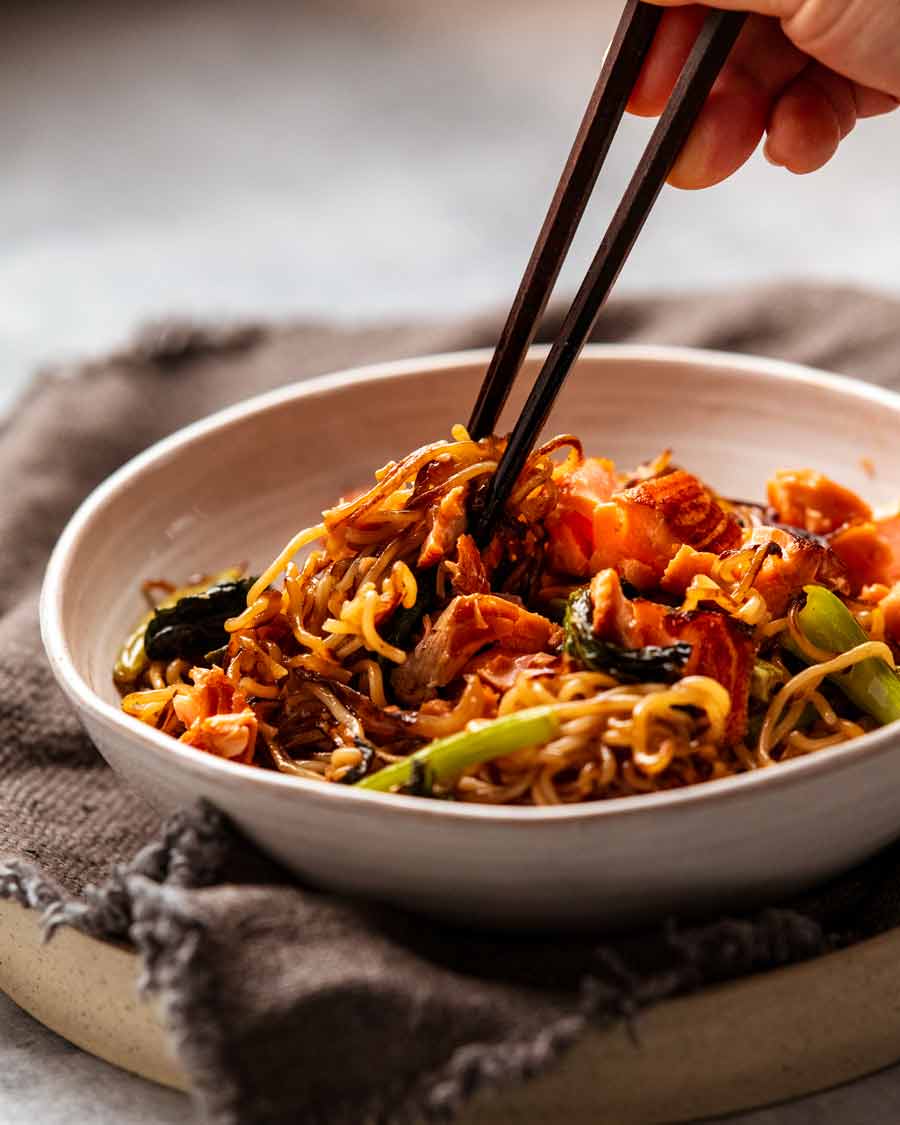 Palillos recogiendo fideos de salmón teriyaki