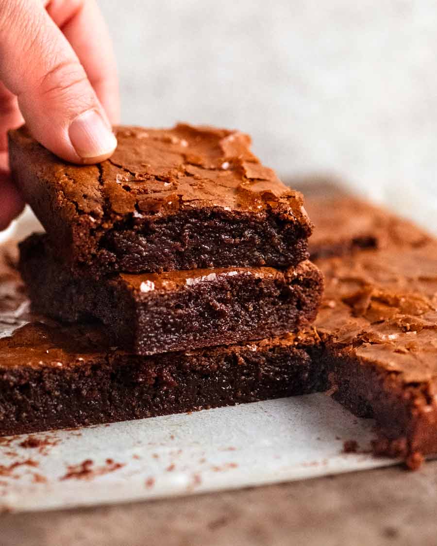 Foto de primer plano de la mano recogiendo un trozo de brownies de chocolate sin harina (sin gluten)