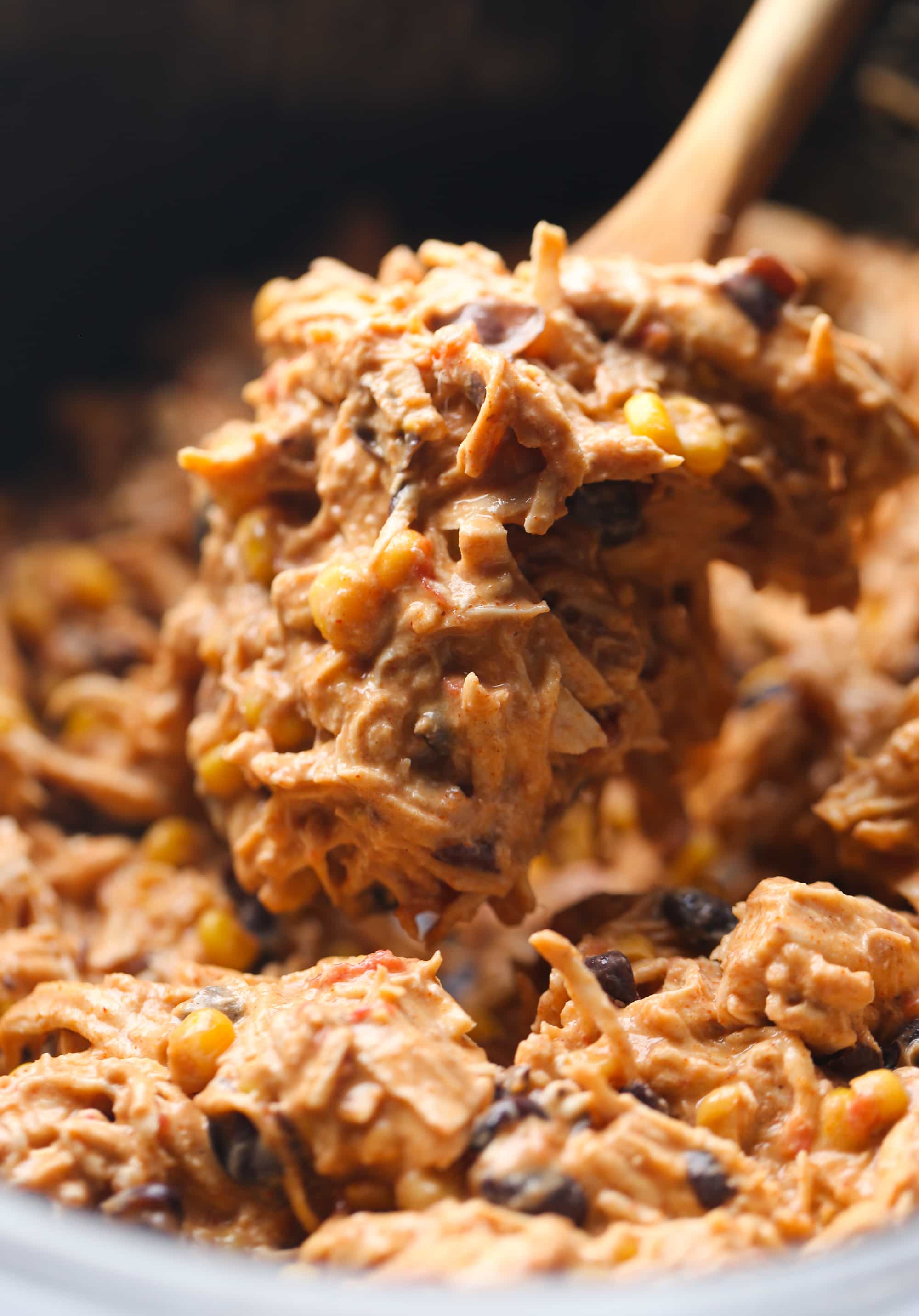 ¡Recetas fáciles de pollo crockpot para cenas deliciosas y manos libres entre semana! Desde sopas de pollo, chiles, recetas de pollo desmenuzado y más. Una cuchara de madera sacando una porción de pollo Fiesta de una olla