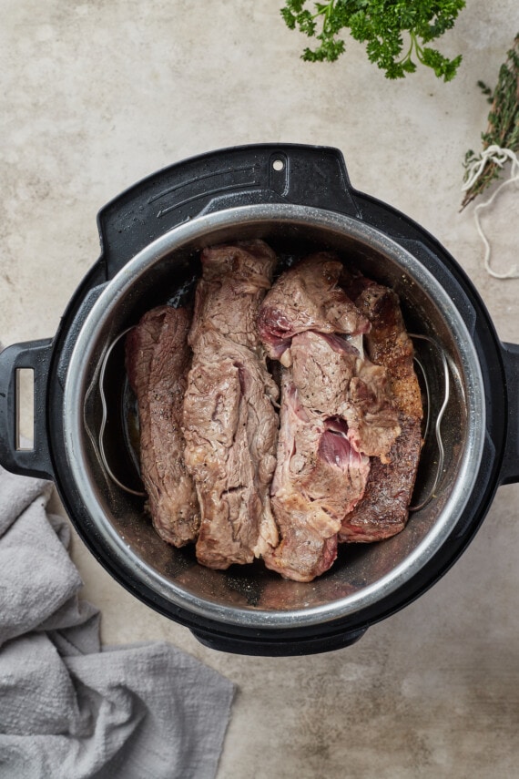 Las costillas de res doradas se agregan al caldo en una olla instantánea.