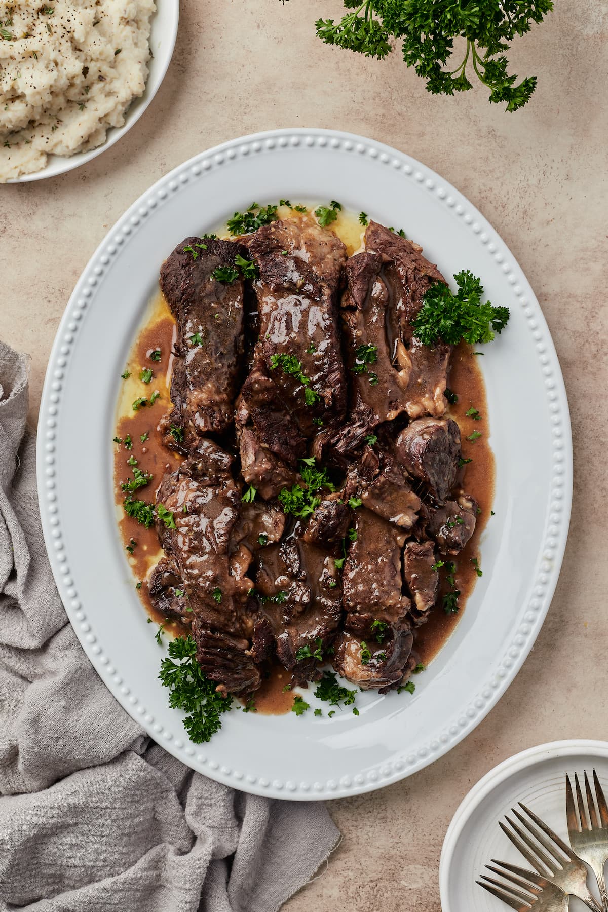 Vista superior de jugosas costillas de ternera cubiertas con salsa de vino tinto en un plato blanco.