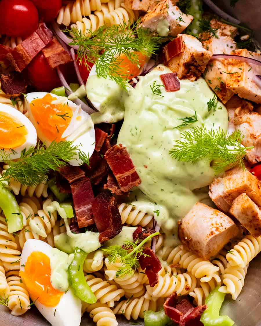 Foto de primer plano de ensalada de pasta con aderezo ranch de aguacate en una ensaladera