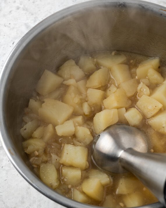 Se usa una licuadora de inmersión para hacer puré de papas en una olla.