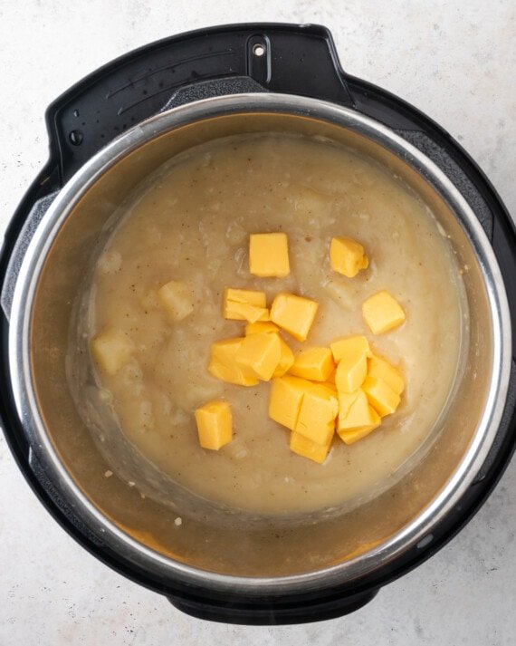 Se agregan trozos de queso de naranja a la olla instantánea con el puré de papas.