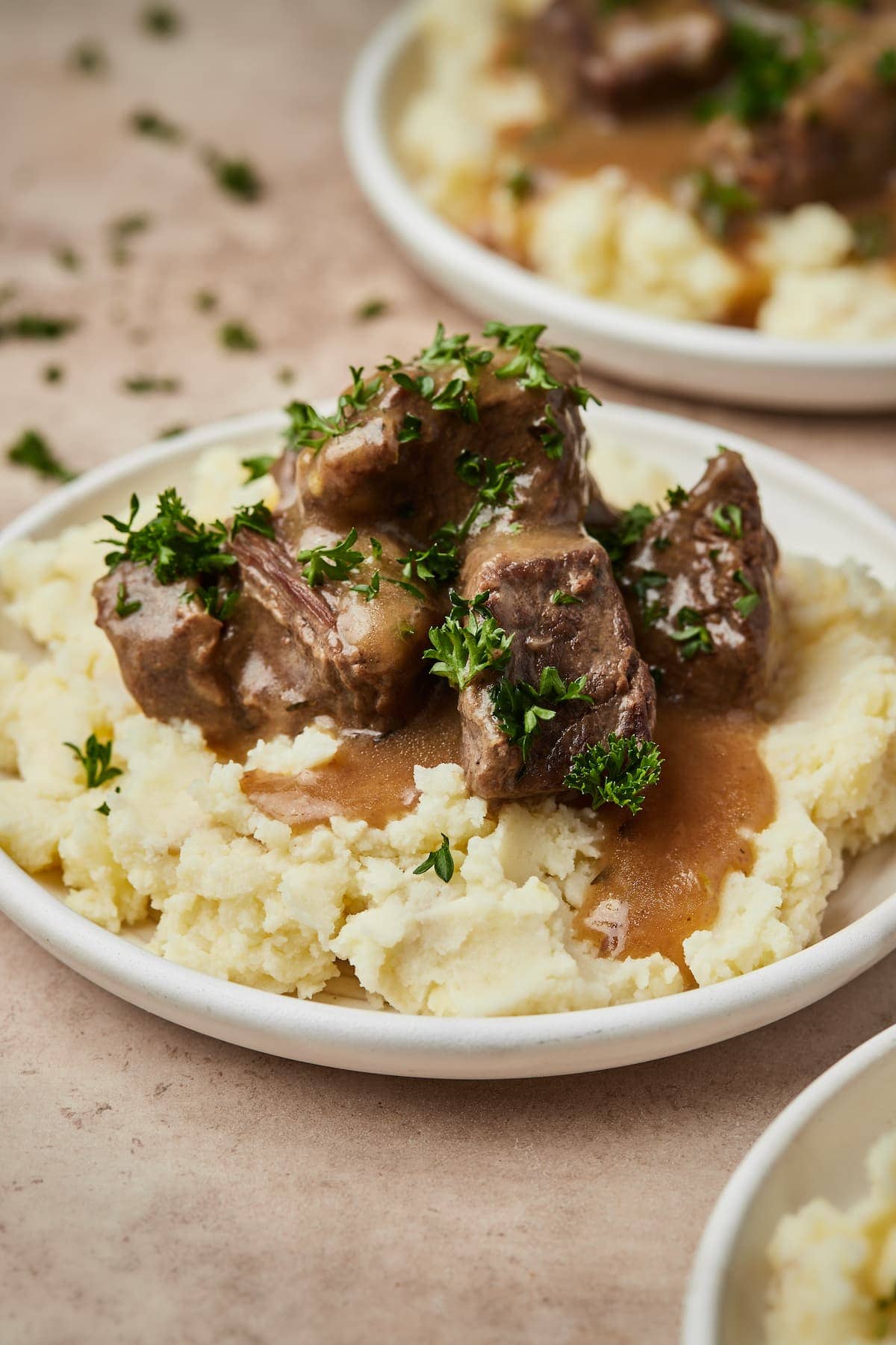 Carne de res en cubos Instant Pot y salsa servida sobre una cama de puré de papas en un plato.