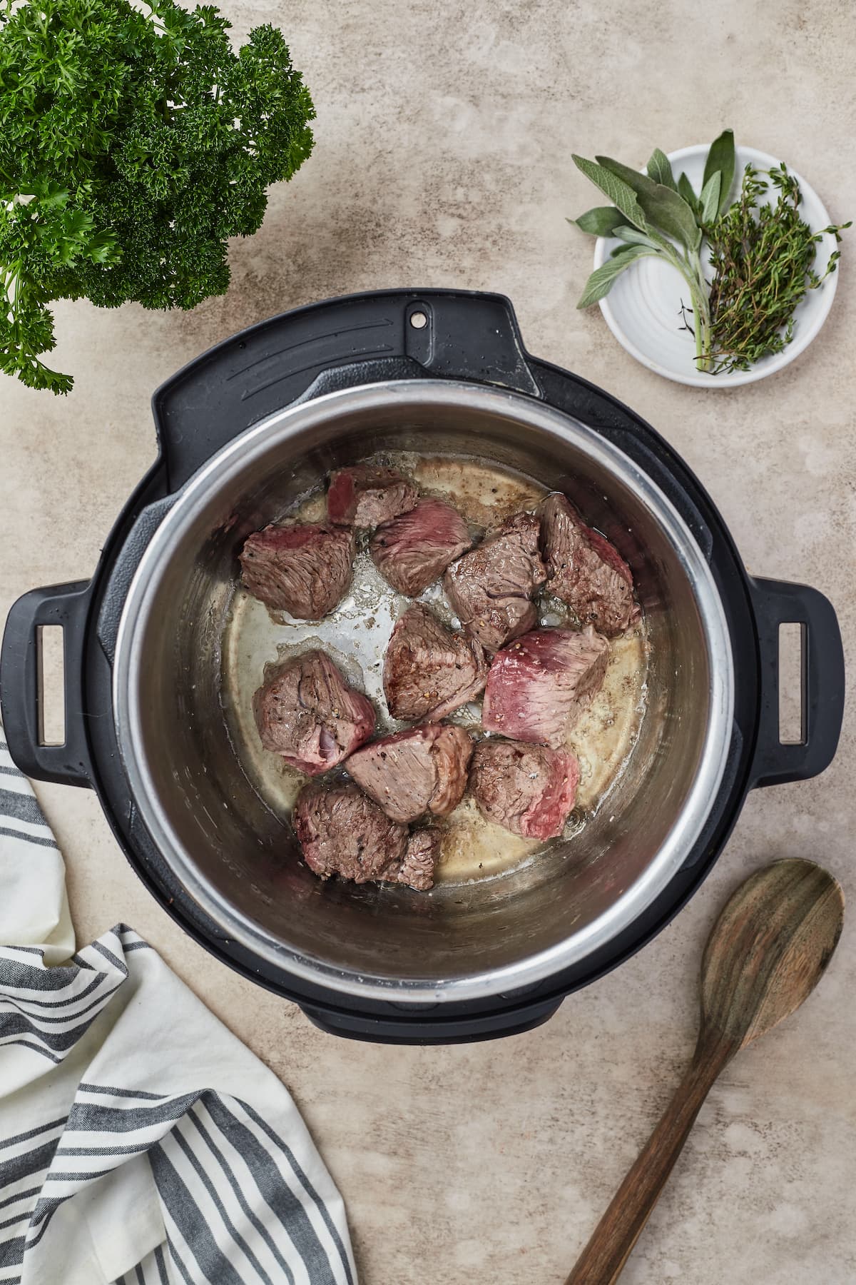 Trozos de carne de res sazonados que se doran en el tazón de una olla instantánea.