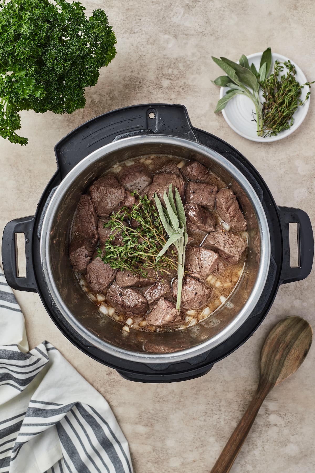 Los trozos de carne dorada se agregan a una olla instantánea con cebolla, ajo y hierbas.
