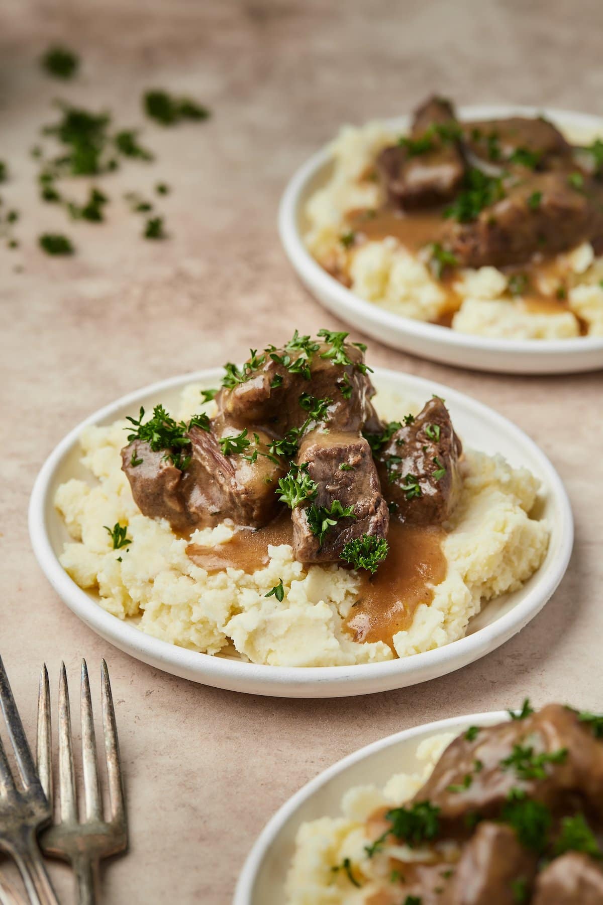 Platos de carne de res en cubos Instant Pot y salsa servidos sobre puré de papas.