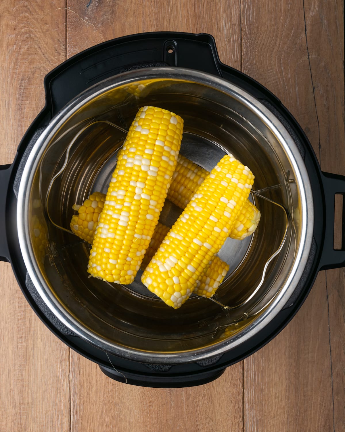 Instant Pot Corn on the Cob es, con mucho, la forma más fácil de disfrutar maíz fresco en minutos. Una guarnición fresca de verano cubierta con mantequilla de hierbas casera. Vista superior de mazorcas de maíz sin cáscara dentro de una olla instantánea.