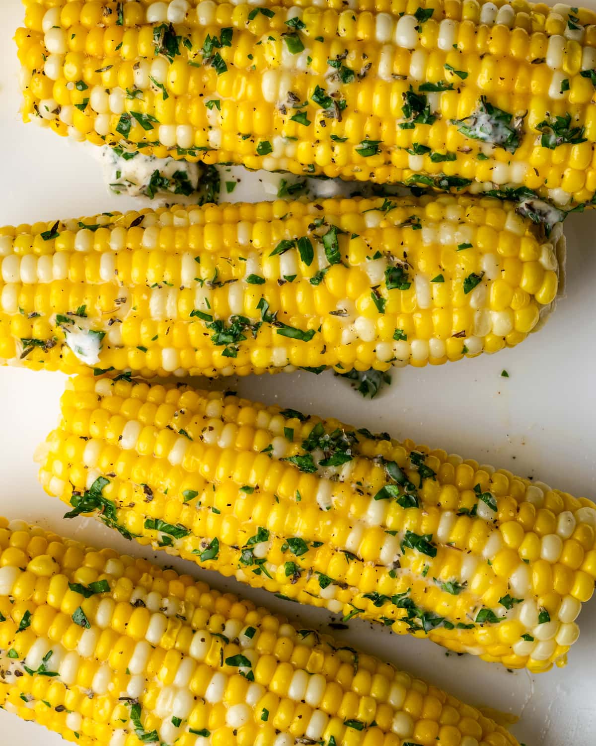 Instant Pot Corn on the Cob es, con mucho, la forma más fácil de disfrutar maíz fresco en minutos. Una guarnición fresca de verano cubierta con mantequilla de hierbas casera. Vista superior de la mazorca de maíz cubierta con mantequilla y hierbas.