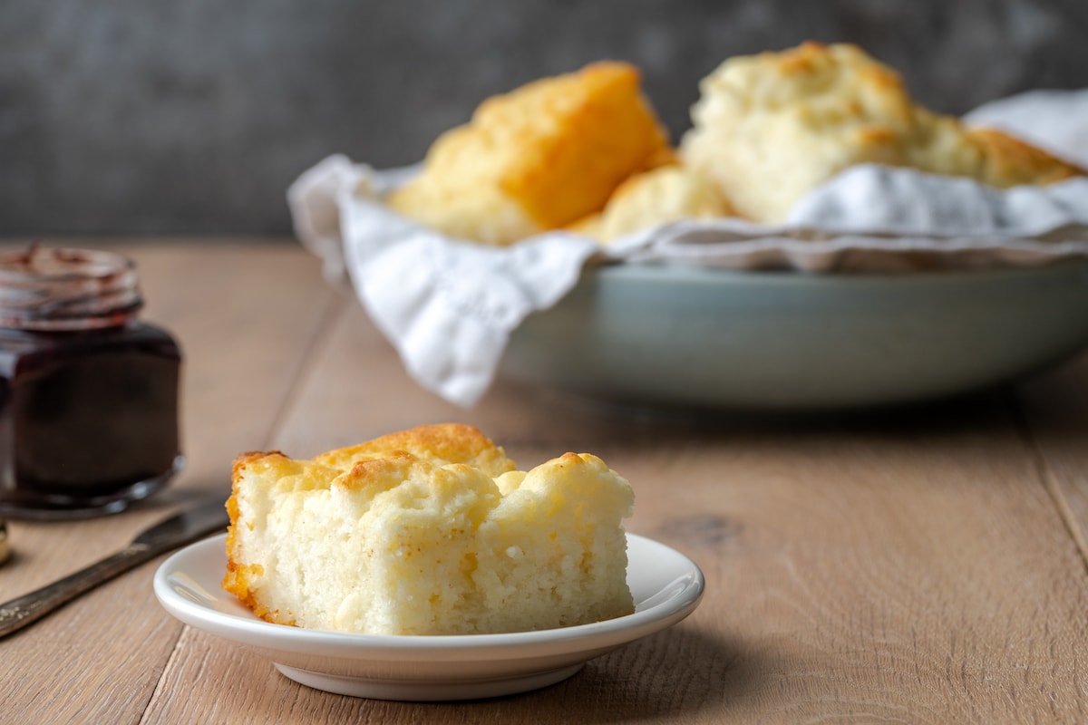 ¡Estas celestiales galletas Butter Swim se hornean doradas en mantequilla para obtener una textura increíblemente suave, húmeda y lista para rebanar! Una sola galleta en un plato blanco, con más galletas nadadoras de mantequilla en un tazón en el fondo.