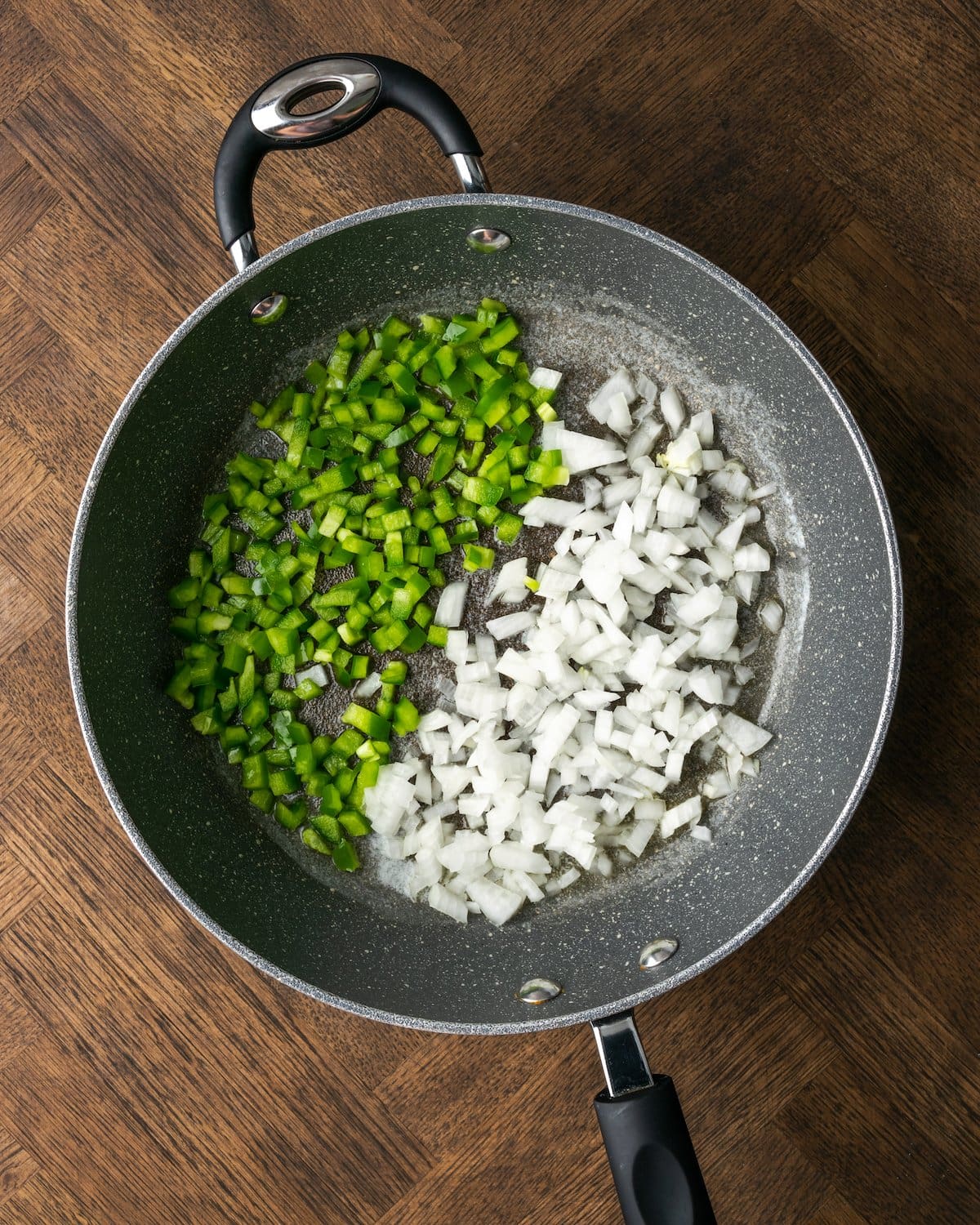 Cebollas picadas y pimientos verdes en una sartén.
