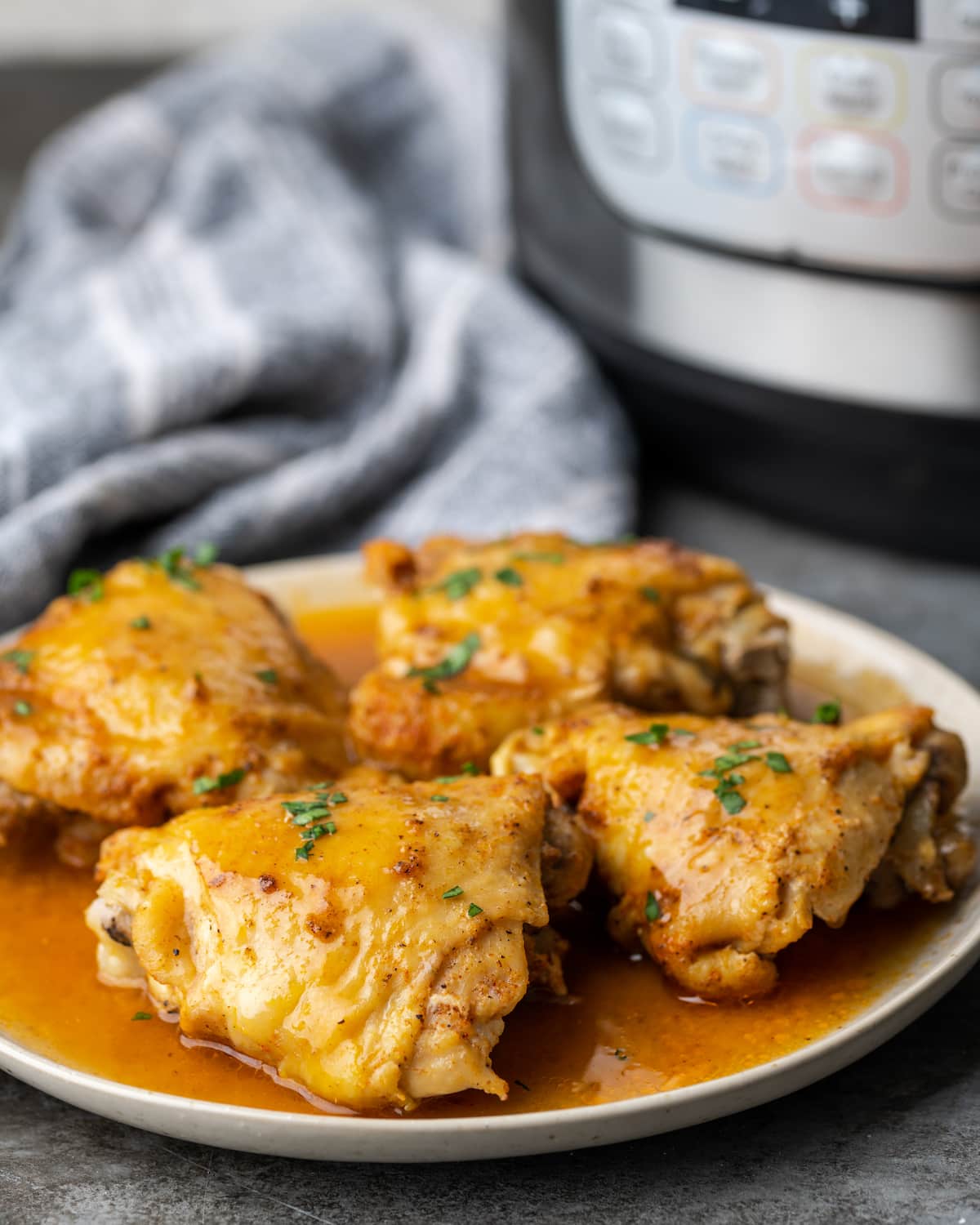 Cuatro muslos de pollo instantáneos en un plato cubierto con salsa.