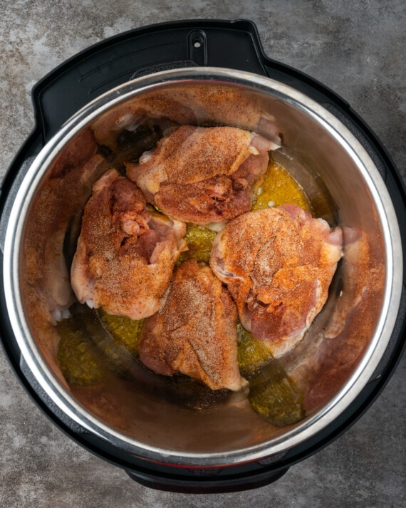 Vista superior de muslos de pollo crudos en el recipiente de la olla instantánea.