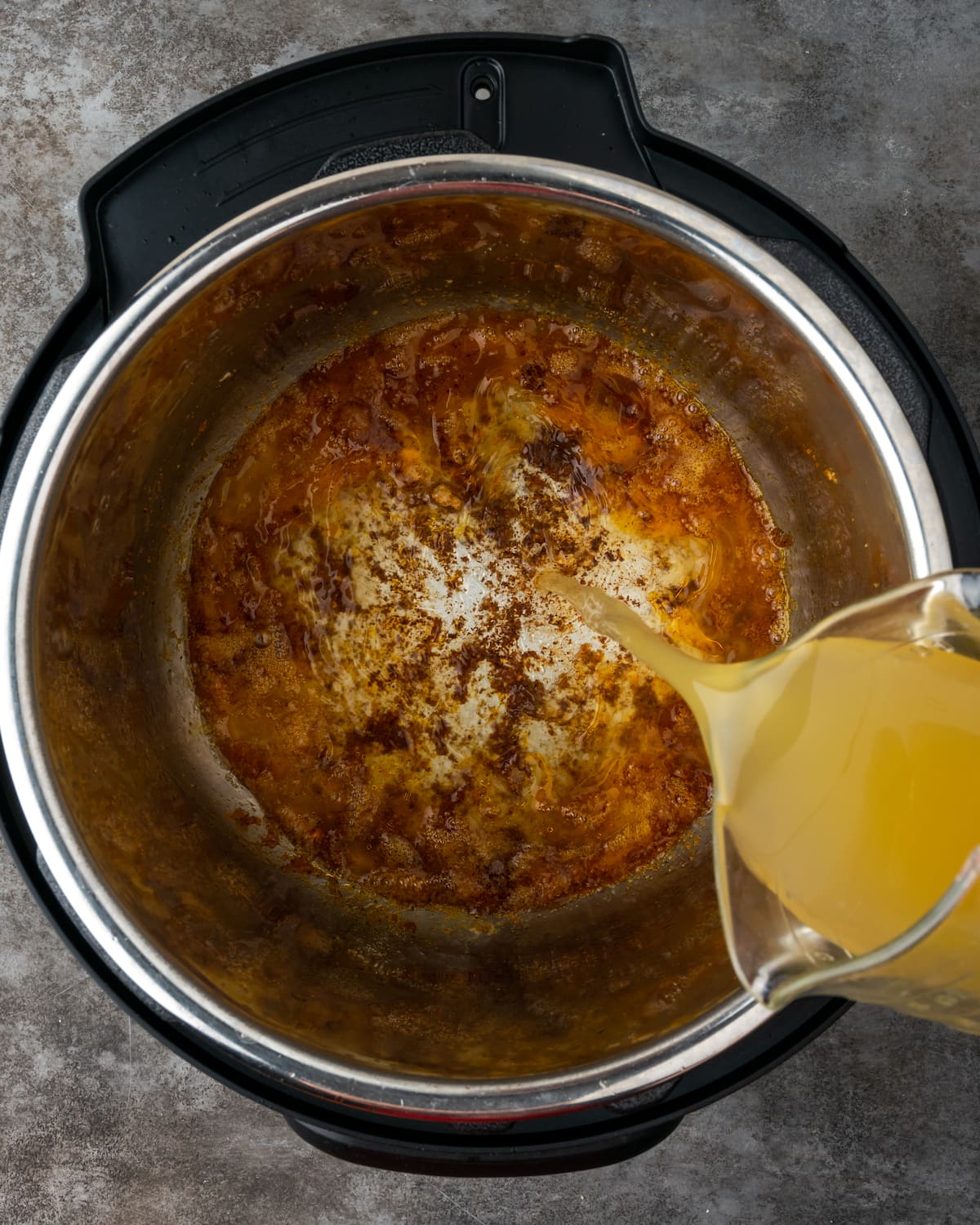 El caldo de pollo se vierte en la olla instantánea para desglasar.