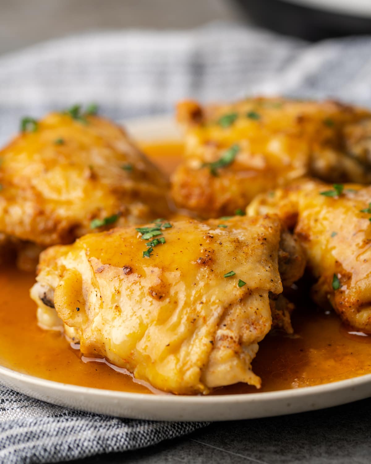Cuatro muslos de pollo instantáneos en un plato cubierto con salsa.