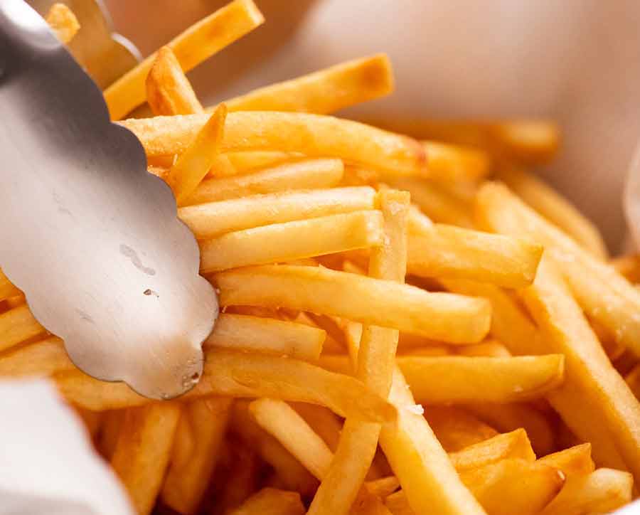 Pinzas recogiendo papas fritas caseras