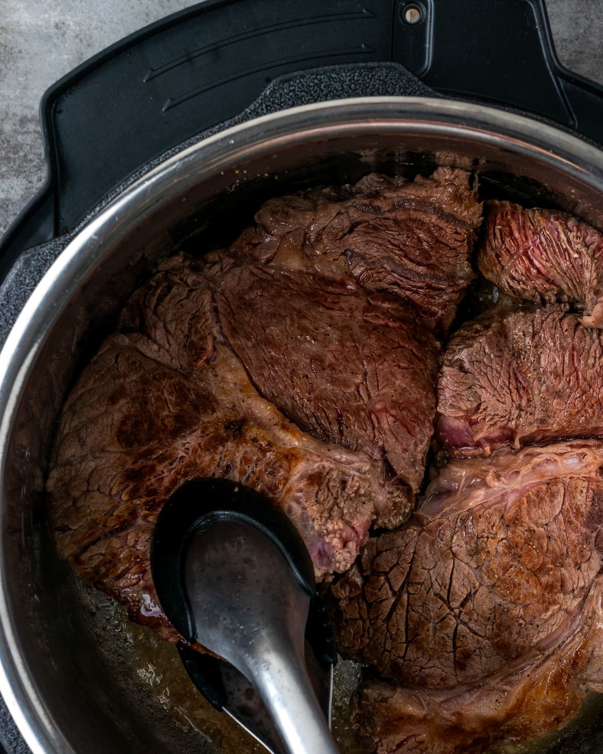 Las pinzas se usan para mover el asado de mandril chamuscado dentro de Instant Pot.