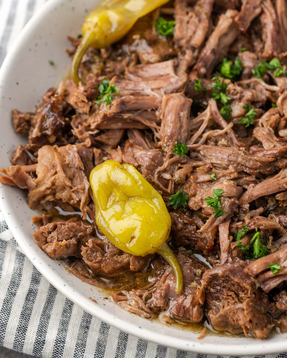 Cierre la vista superior de Instant Pot Mississippi Pot Roast en un plato para servir cubierto con pepperoncini.