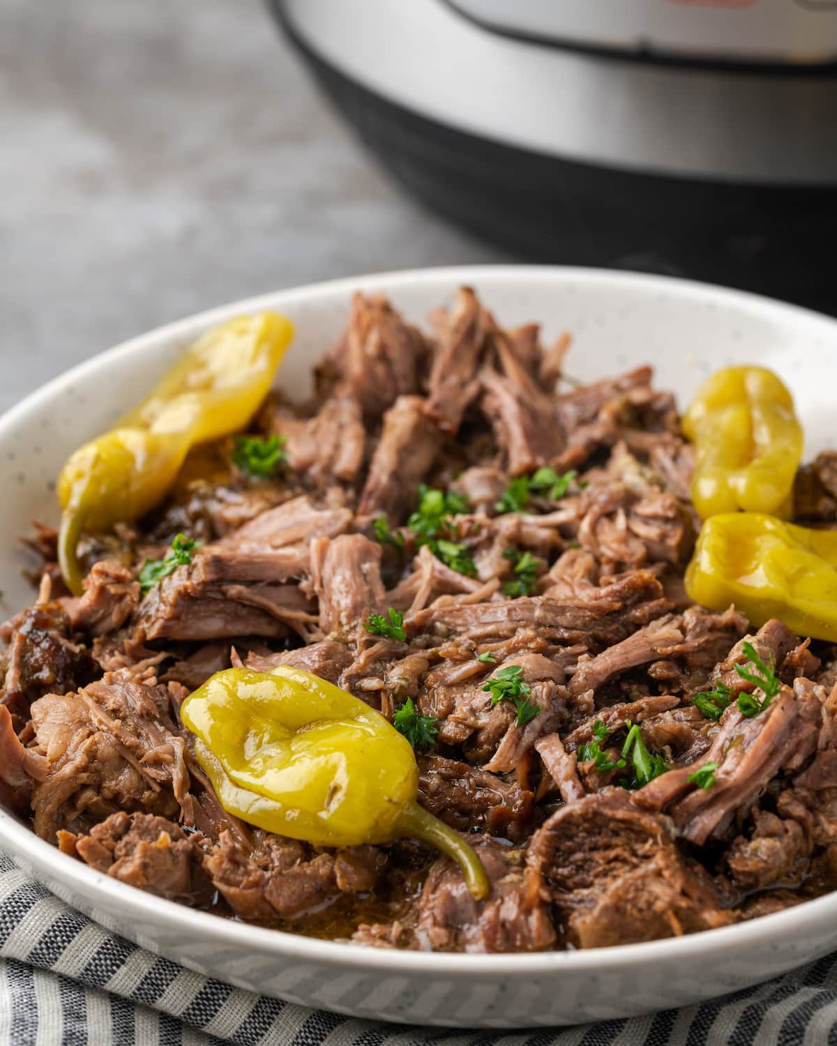 Instant Pot Mississippi Pot Roast en un plato para servir cubierto con pepperoncini.