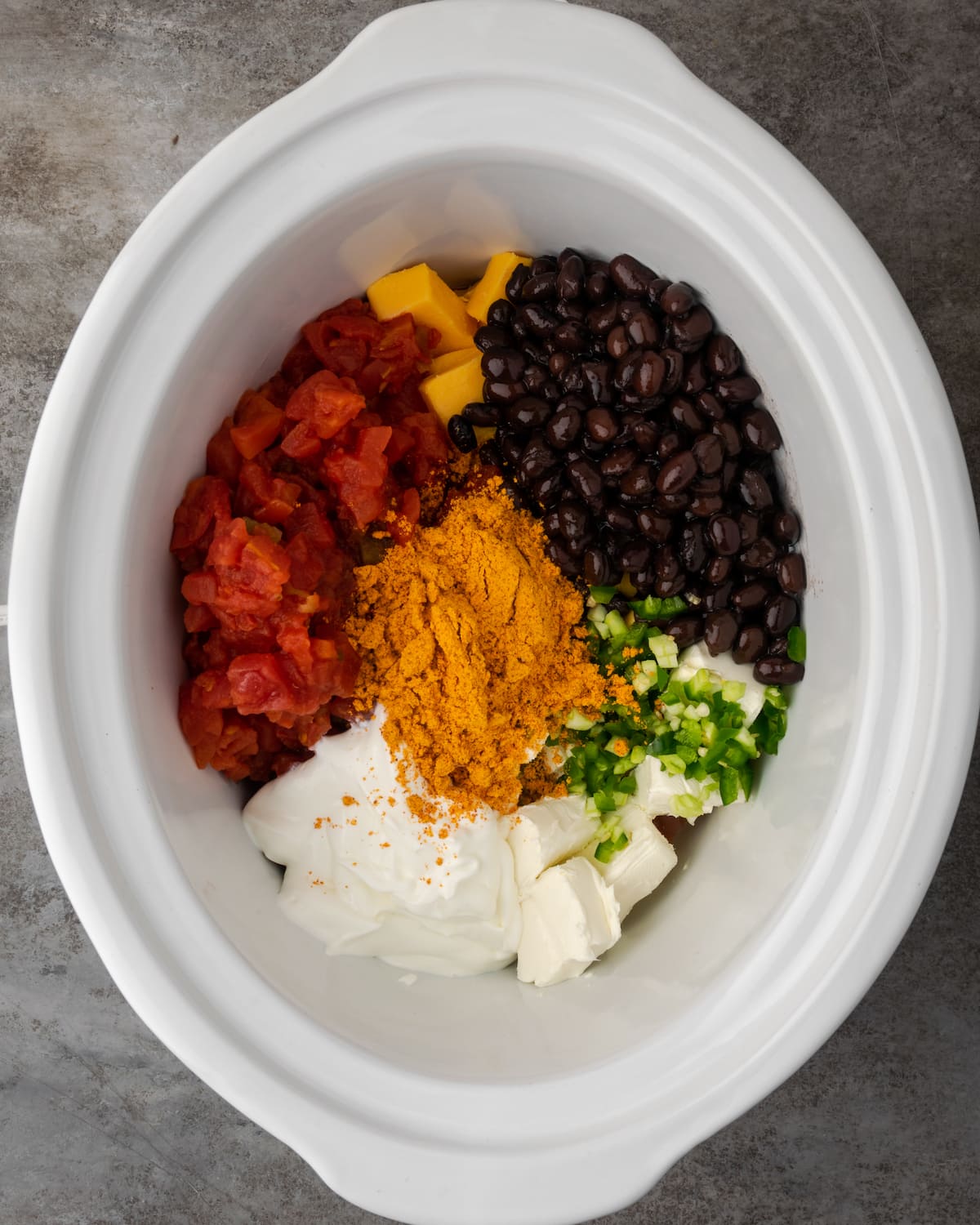 Vista aérea de los ingredientes de la salsa de nacho de pollo ensamblados en el tazón de una olla de barro.