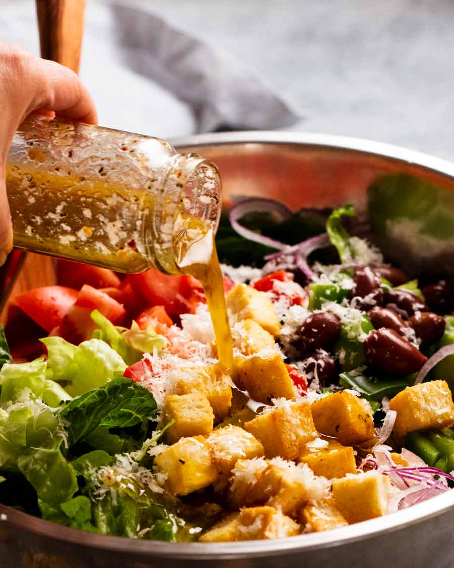 Verter aderezo italiano sobre mega ensalada italiana