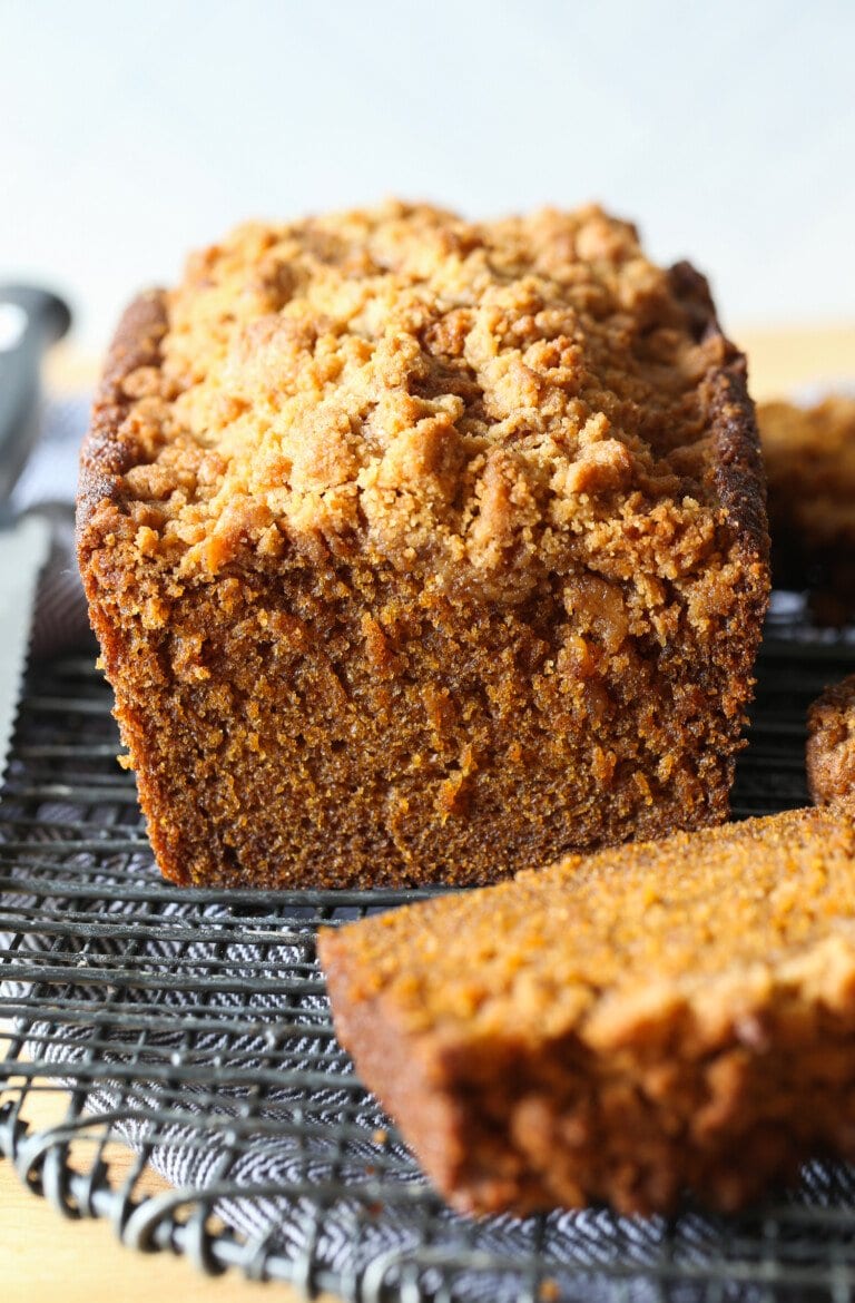 Una rebanada cortada de una hogaza de pan de calabaza en una rejilla para enfriar.