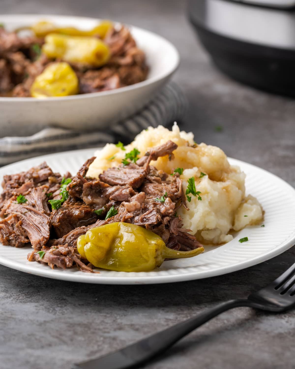 Asado a la olla de Mississippi en un plato blanco junto al puré de papas.