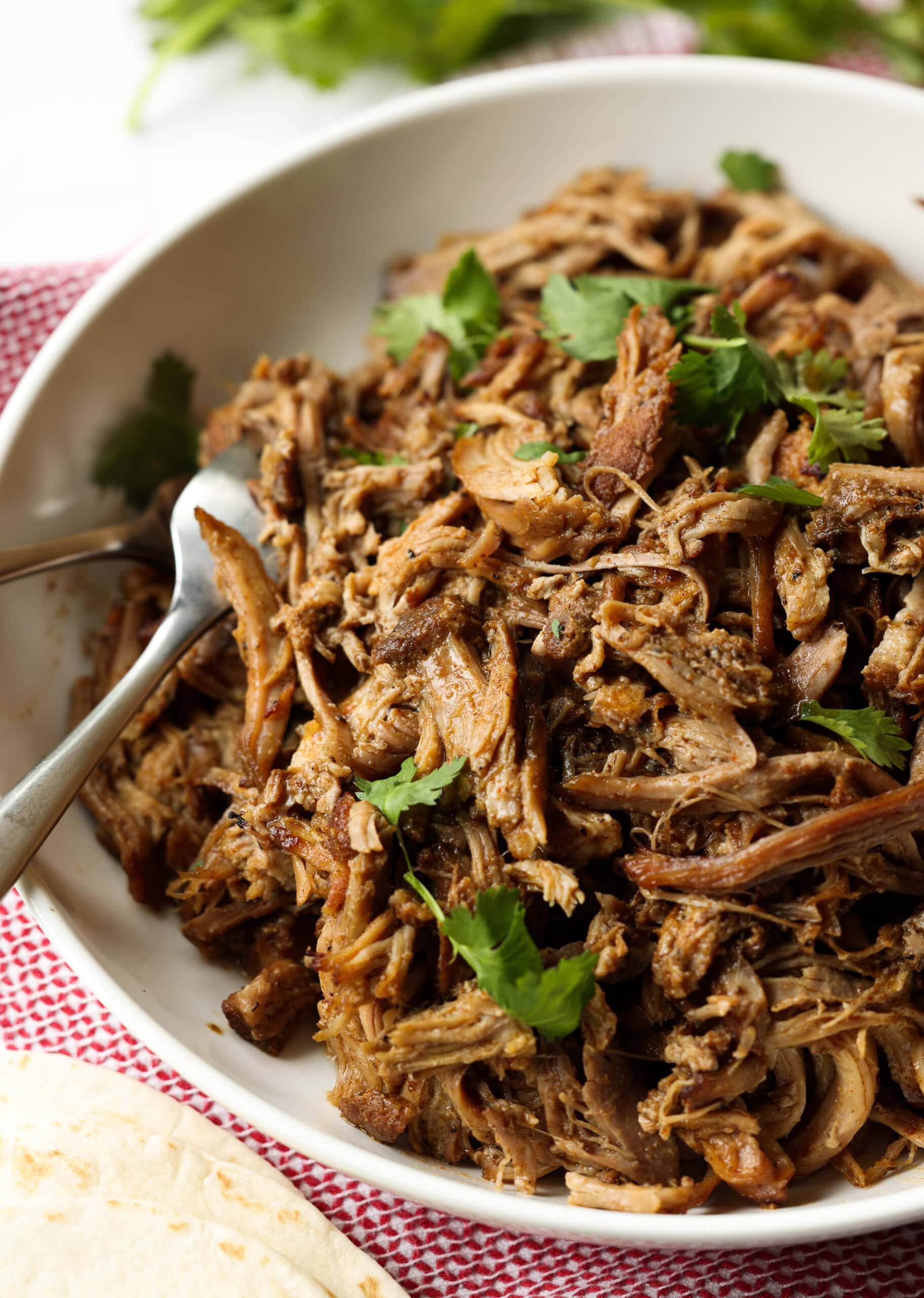 carnitas de olla de cocción lenta en un recipiente poco profundo desmenuzado con un tenedor