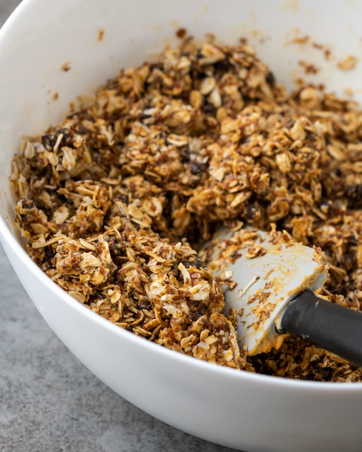 ¡Estas mordidas energéticas sin hornear con mantequilla de maní y chocolate toman solo unos minutos para prepararse! Una receta fácil de bolitas de proteínas para un refrigerio saludable. Mezcla energética para picar en un tazón blanco con una espátula.