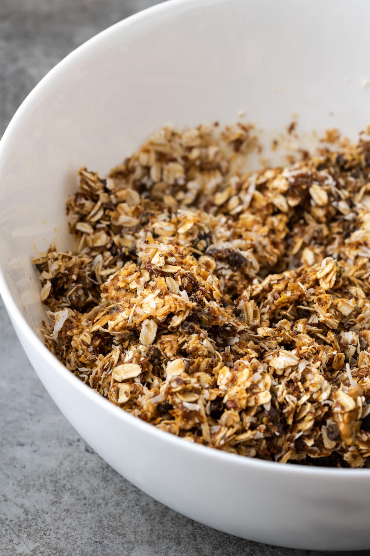¡Estas mordidas energéticas sin hornear con mantequilla de maní y chocolate toman solo unos minutos para prepararse! Una receta fácil de bolitas de proteínas para un refrigerio saludable. Mezcla energética para picar en un tazón blanco.