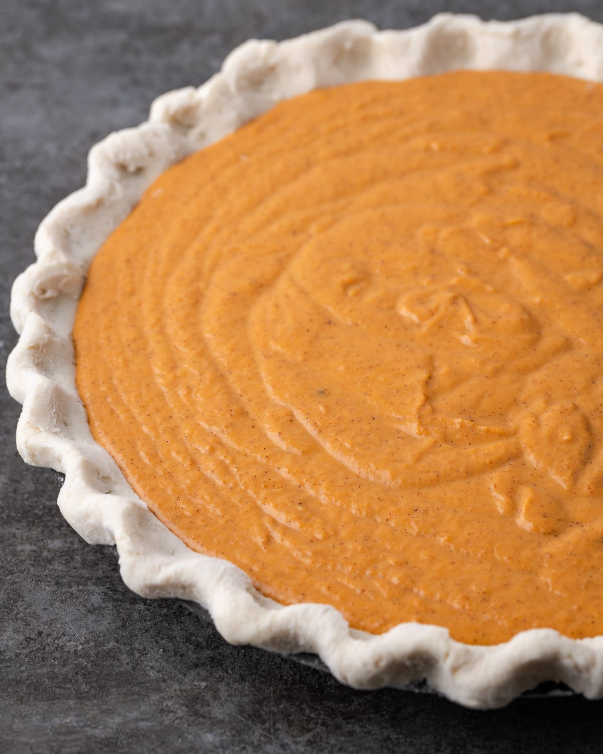 Una masa de pastel sin hornear rellena con relleno de pastel de calabaza.