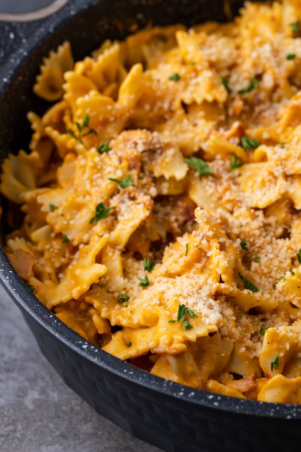 Pasta cremosa de calabaza con tocino en un tazón negro grande para servir.