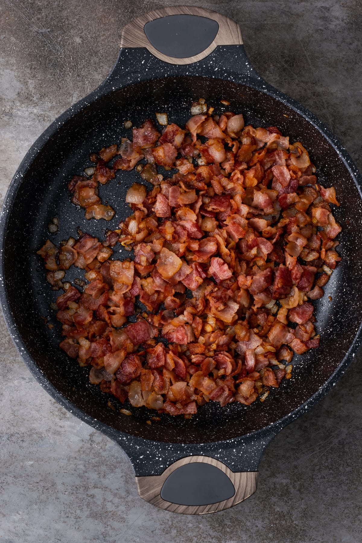 Cebolla caramelizada y tocino en una sartén de hierro fundido.
