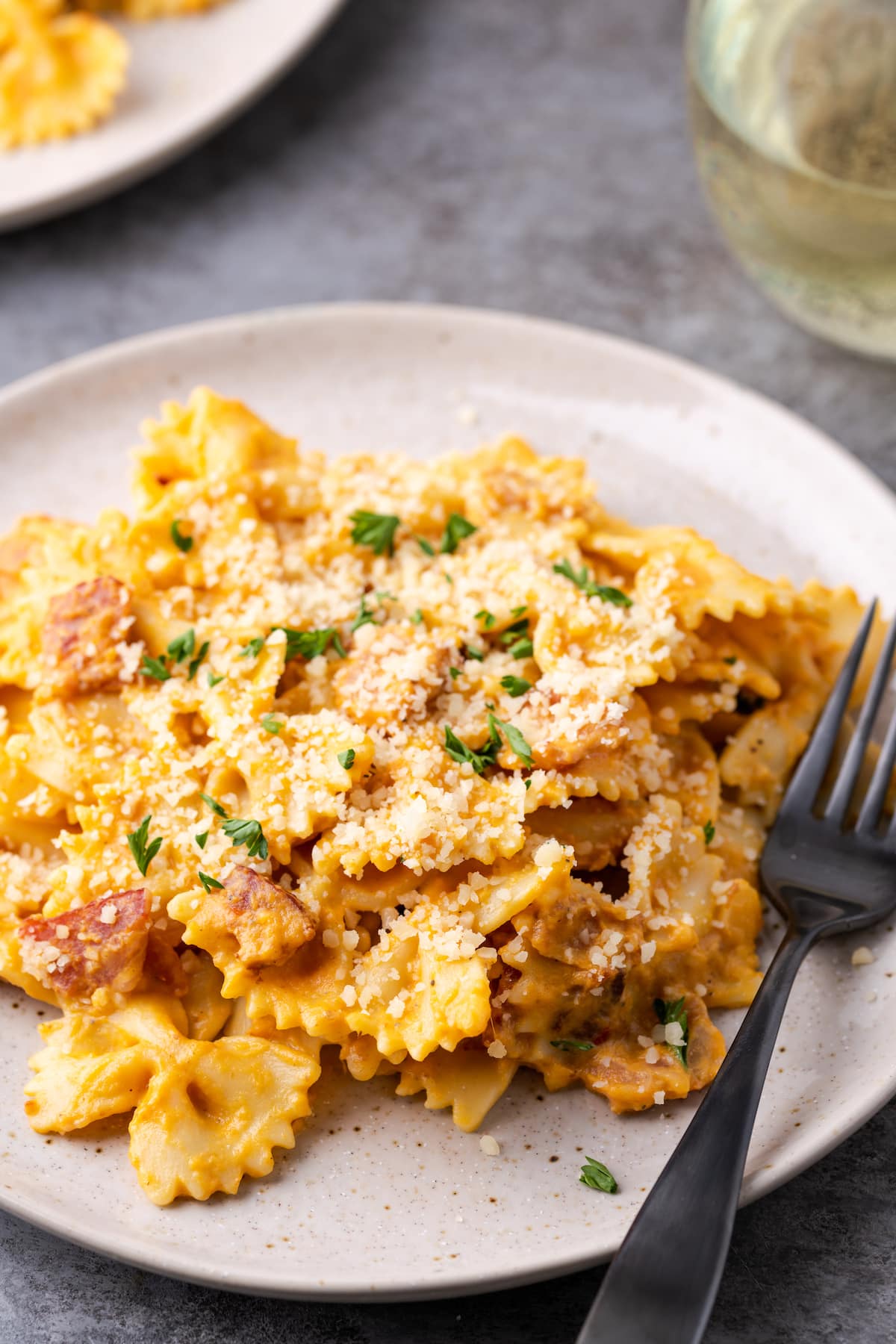 Una porción de pasta de calabaza con tocino en un plato junto a un tenedor.