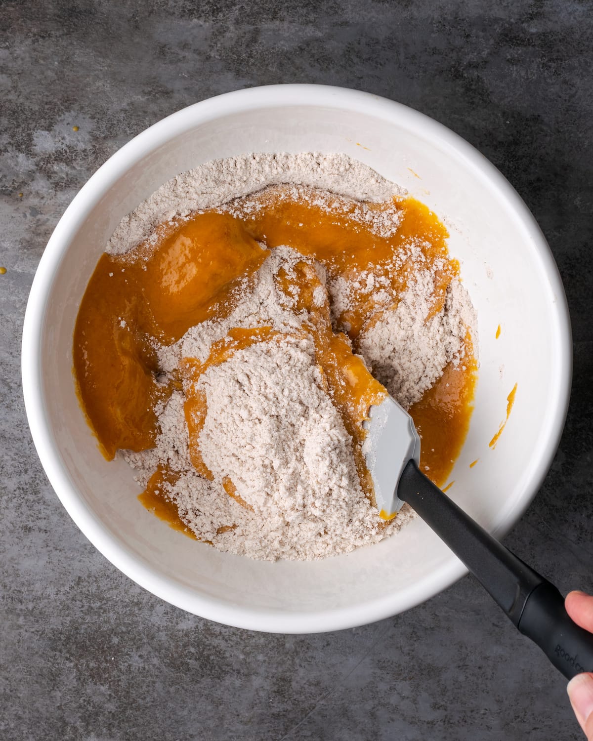 Los ingredientes secos se agregan a un tazón con los ingredientes húmedos para la masa de pastel de calabaza.
