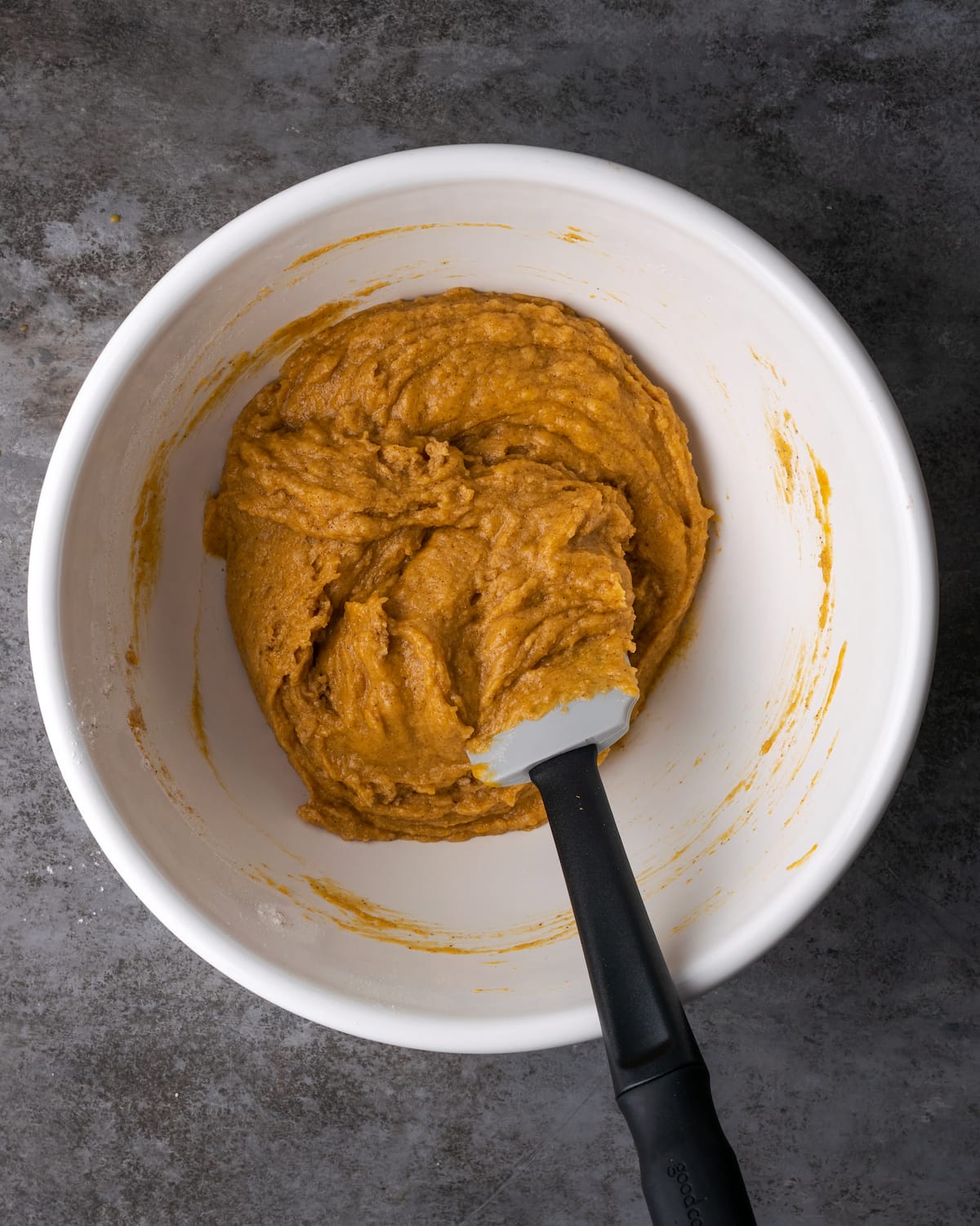 Masa de pastel de calabaza en el fondo de un tazón con una espátula.
