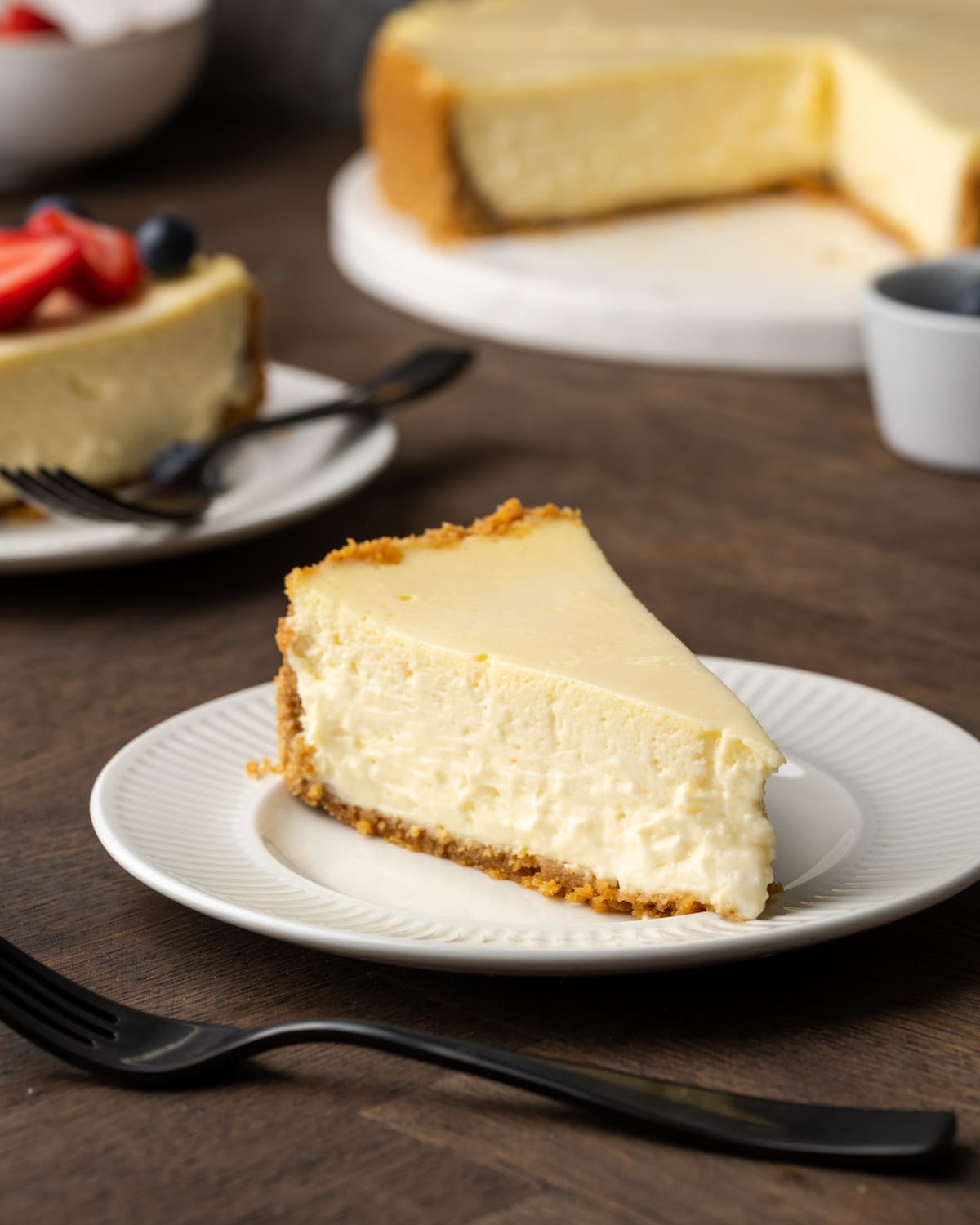 Una rebanada de tarta de queso con crema agria en un plato blanco.