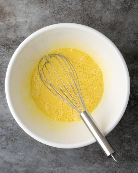 La mezcla de huevo para la masa de tarta de queso en un tazón grande con un batidor.
