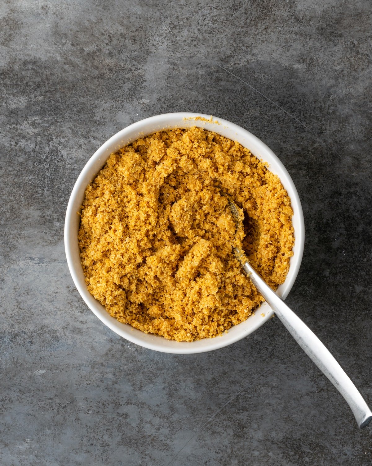 Un tazón de migas de galleta graham con una cuchara.