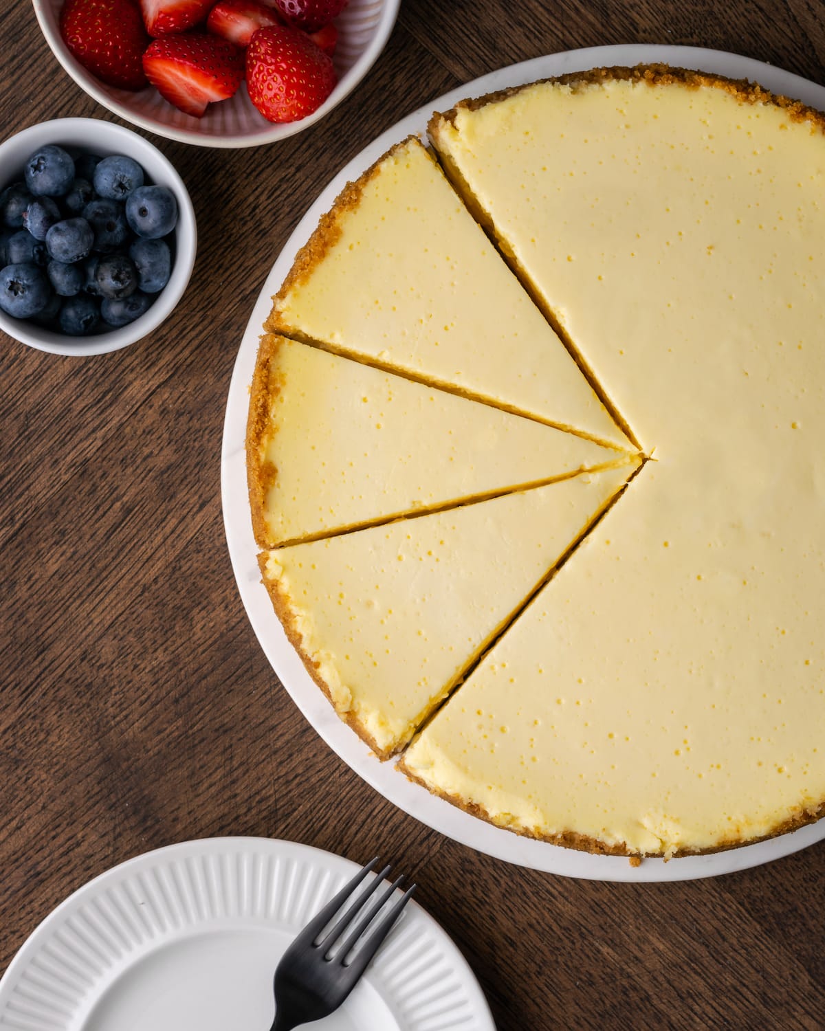 Vista aérea de un pastel de queso con crema agria con tres rebanadas cortadas.