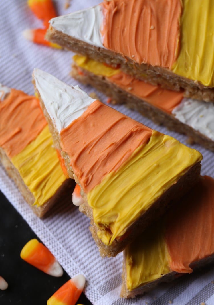 Scotcheroos de maíz de caramelo decorados con caramelos de colores, apilados uno encima del otro.