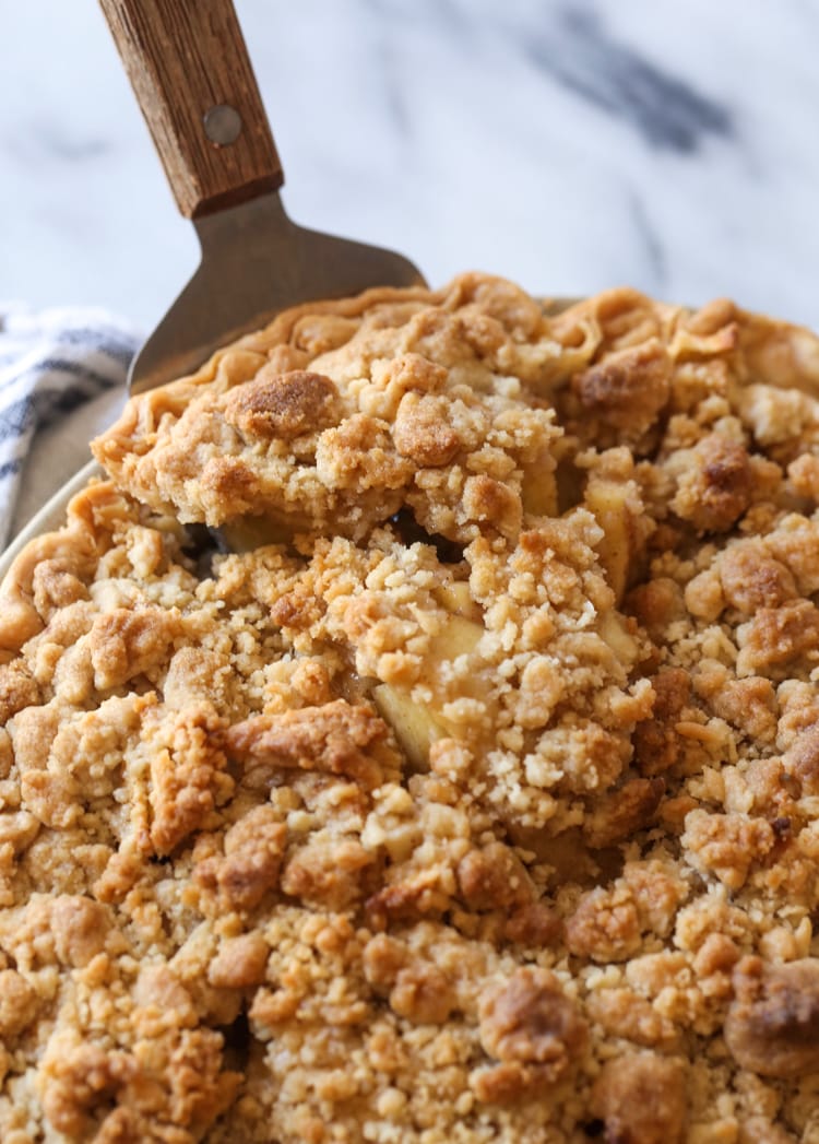 Una rebanada de tarta de manzana holandesa se levanta de un molde para tarta.
