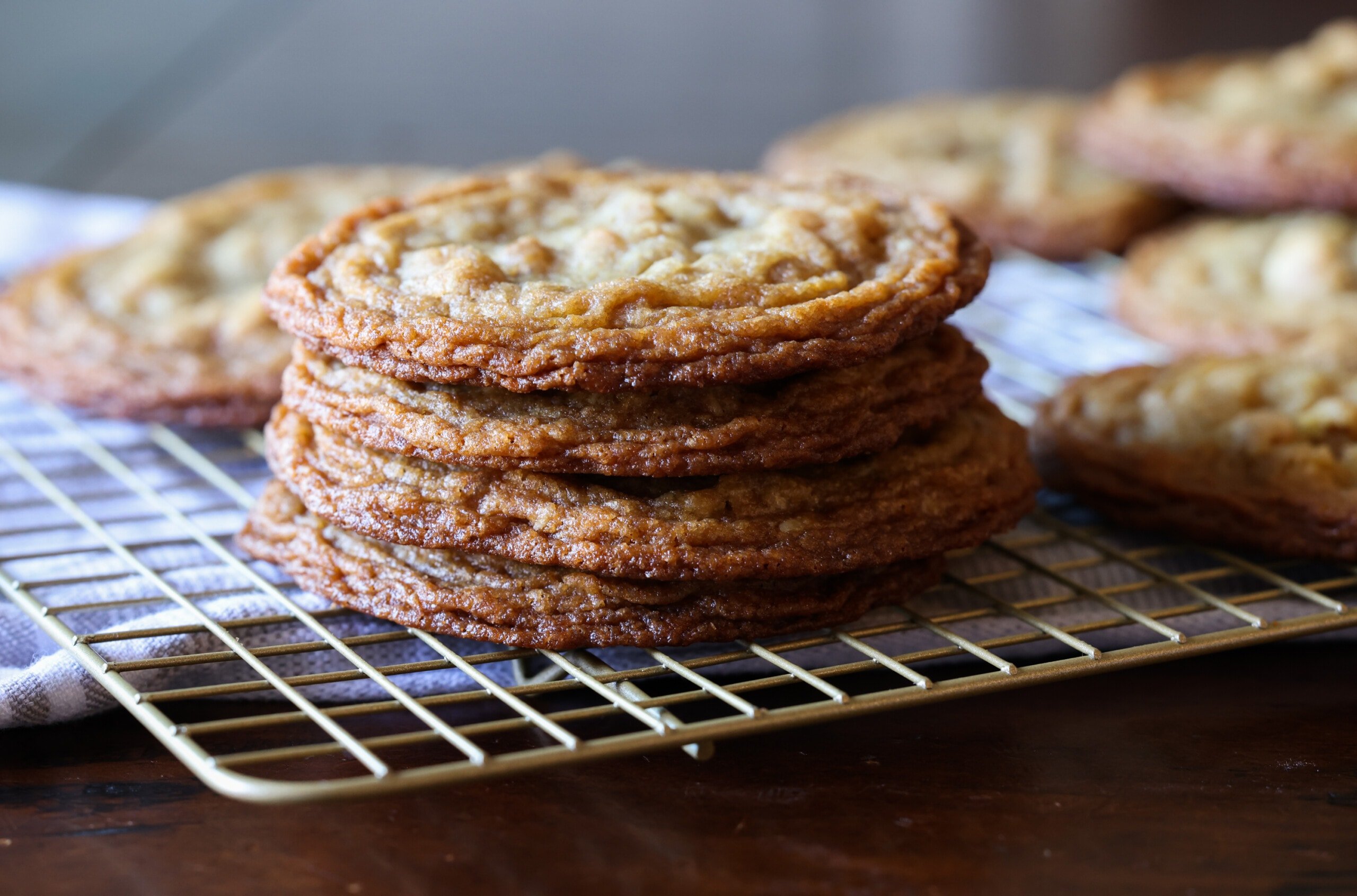 Estas galletas de nuez ultra masticables están hechas con dos tipos de azúcar, un método de golpear la sartén que le da bordes crujientes y mantecosos con centros masticables. galletas de nuez apiladas con bordes arrugados