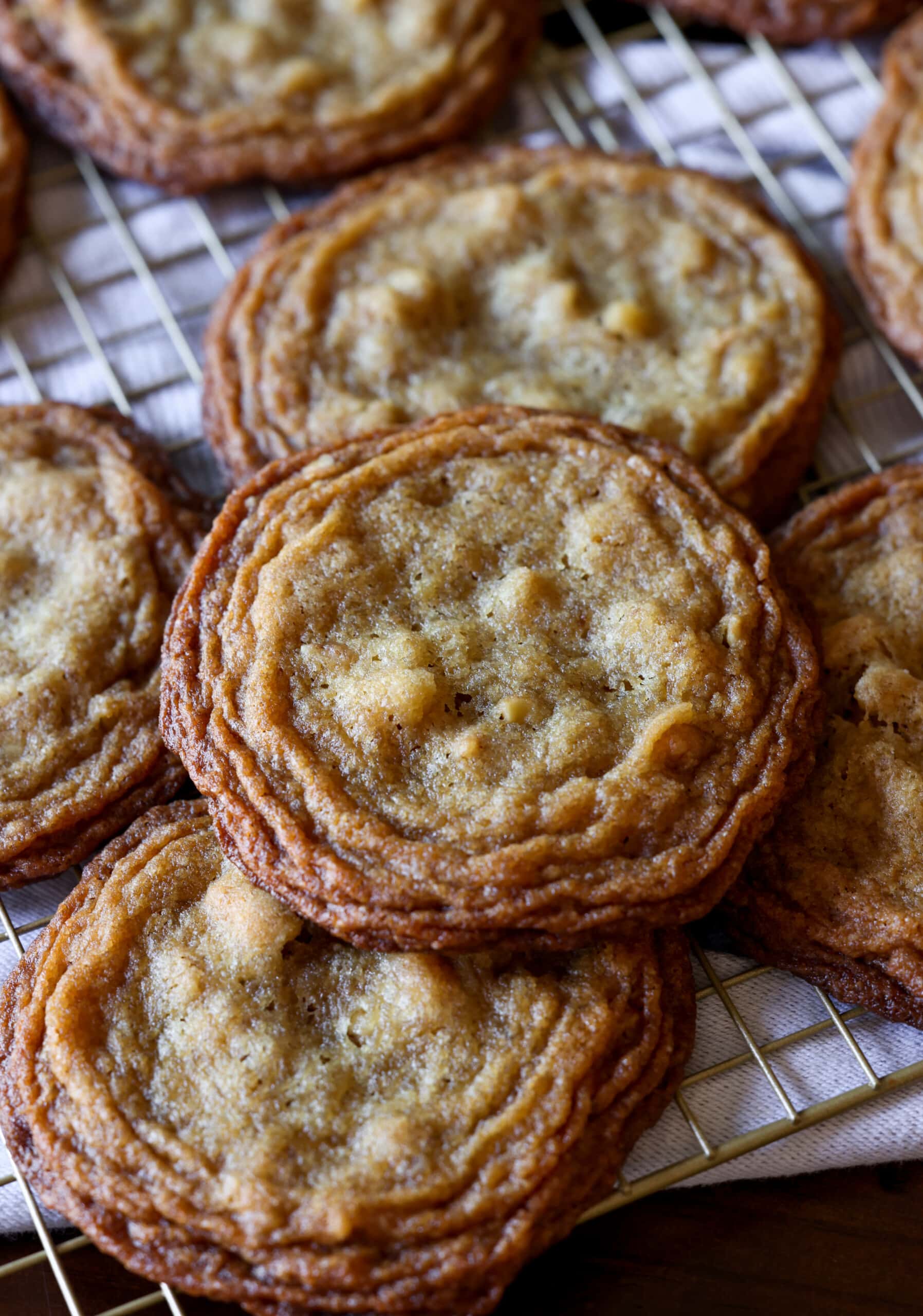 Estas galletas de nuez ultra masticables están hechas con dos tipos de azúcar, un método de golpear la sartén que le da bordes crujientes y mantecosos con centros masticables. pan golpeando galletas de nuez en una rejilla de alambre