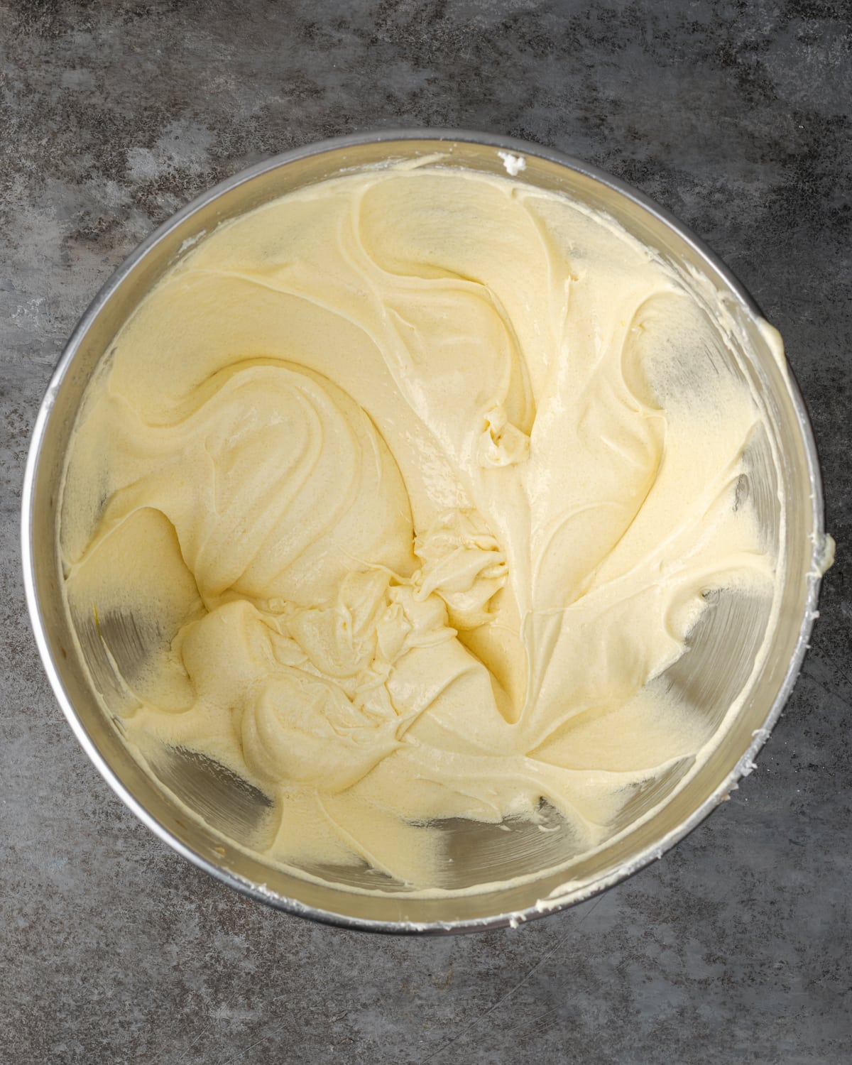 Esta receta de pastel Cannoli transforma un favorito de la panadería en un delicioso pastel de capas de vainilla. ¡Completa con relleno de mascarpone casero! Masa de pastel de cannoli en un tazón de metal.