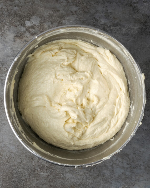 Esta receta de pastel Cannoli transforma un favorito de la panadería en un delicioso pastel de capas de vainilla. ¡Completa con relleno de mascarpone casero! Masa de pastel de cannoli en un tazón de metal.