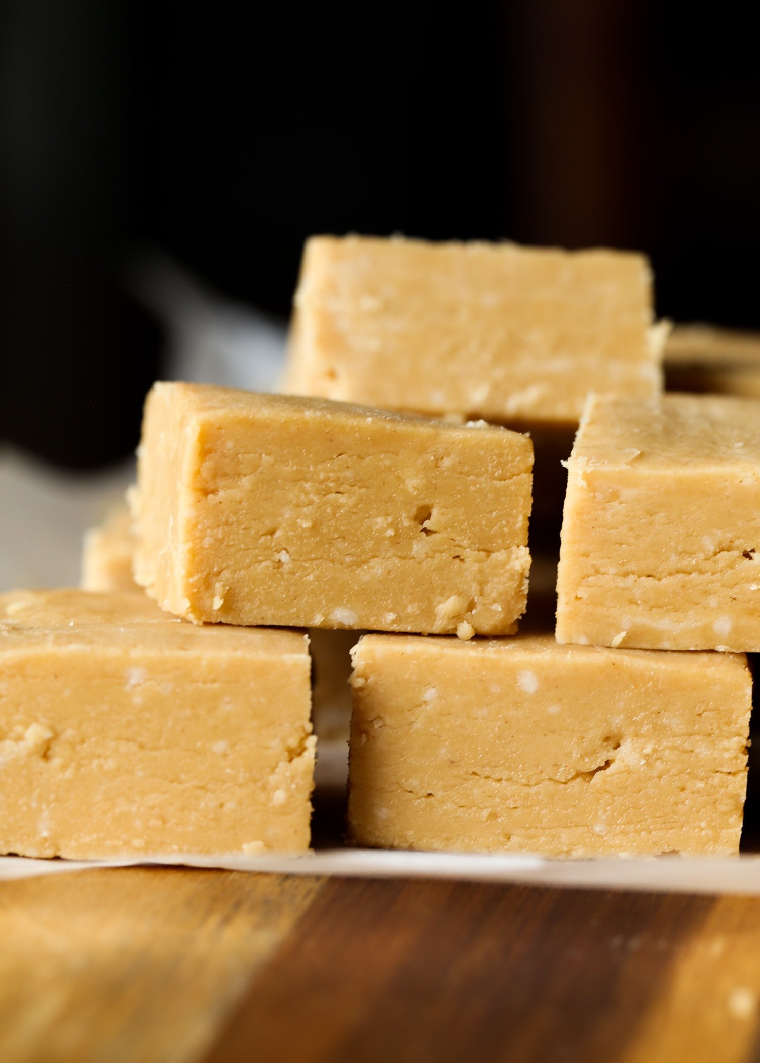 Cuadrados de dulce de mantequilla de maní apilados uno encima del otro en un trozo de papel pergamino.
